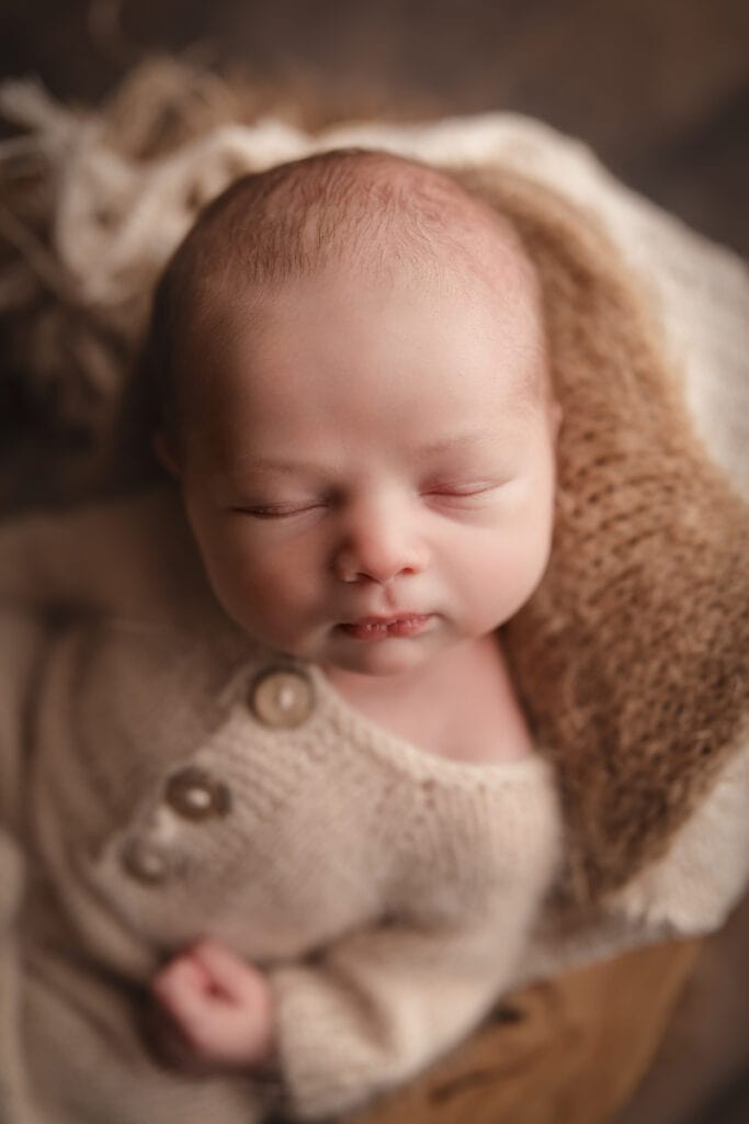 Newborn Photographer, a baby lays sleeping in a knit onesie on blankets