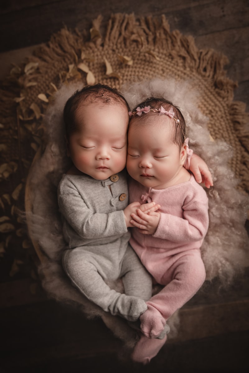 Newborn Photographer, two babies wear onesies and are cradled together in a basket