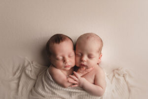 Newborn Photographer, Two twin babies are wrapped together cozily in a blanket