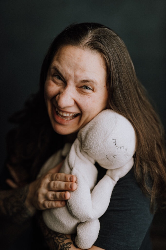 A woman smiles and squeezes a stuffed baby doll